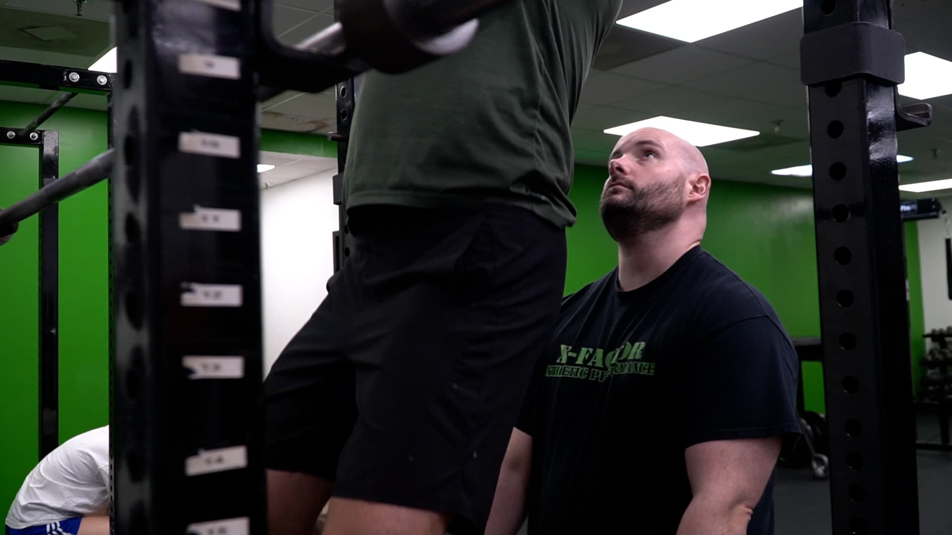Coach Brett Woldanski spotting an athlete at X Factor Athletic Performance, a strength and conditioning gym in Richmond VA